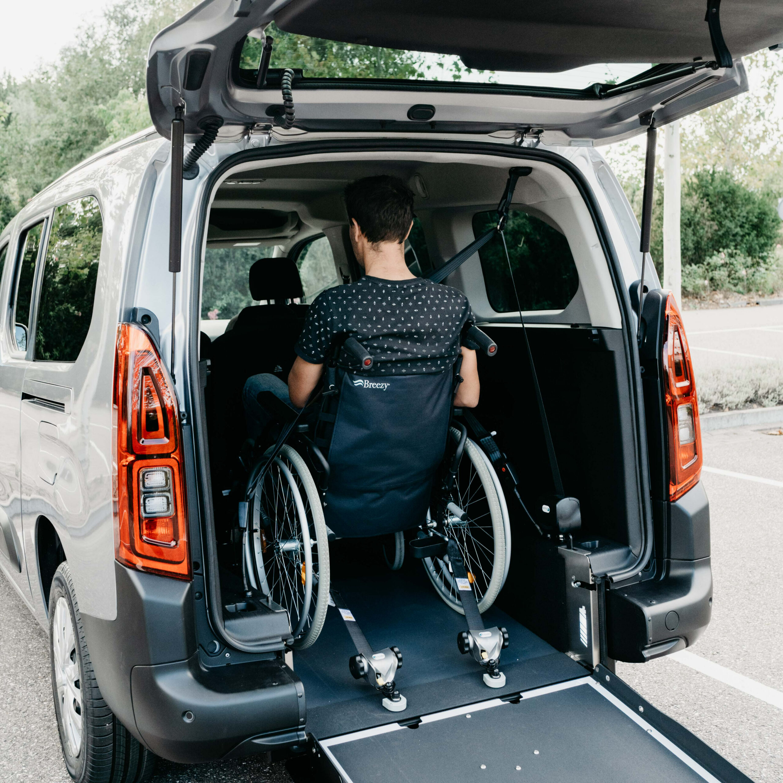 Van Amenage Fauteuil Roulant Transport Personne Handicapee Homme en fauteuil roulant entrant dans un van aménagé avec rampe. Mobilité réduite, transport adapté.